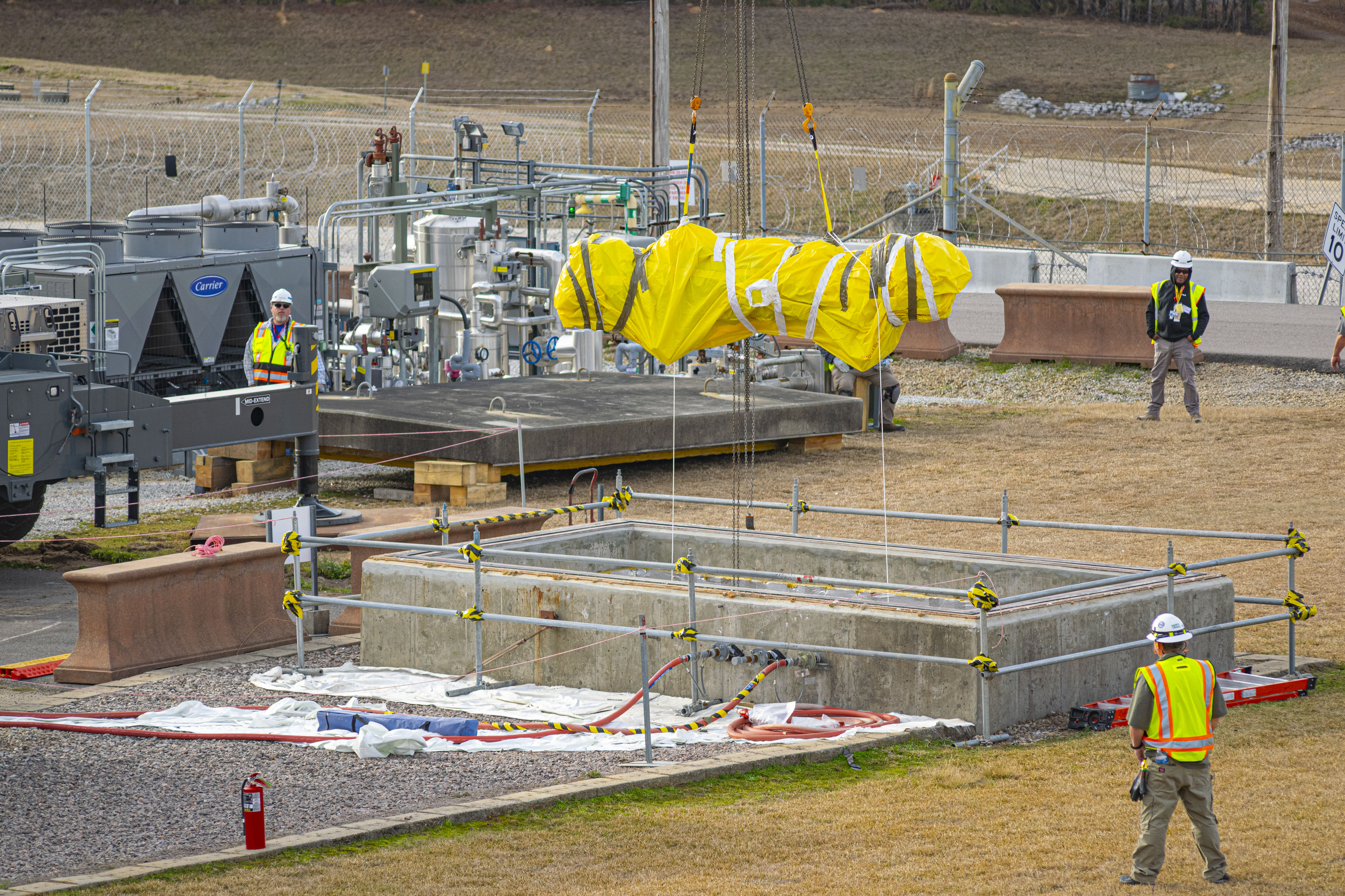 Personnel use a 165-ton crane to lift and remove old equipment through a hatch located above the SRTE facility.